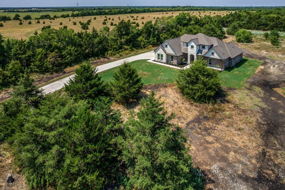 Aerial view of a two-story stone and brick home with driveway